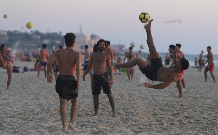 Người dân chơi bóng trên bãi biển tại Tel Aviv, Israel ngày 4-8 - Ảnh: REUTERS