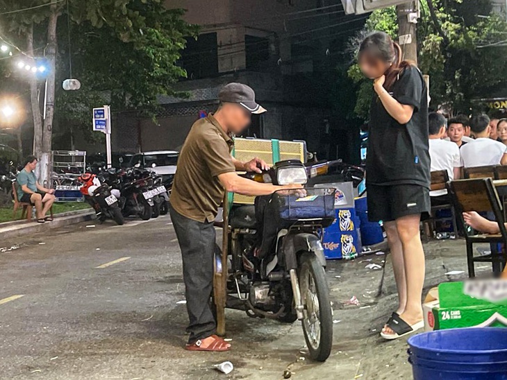 Một người bán hàng rong chở theo loa đến mở nhạc, hát hò tại quán nhậu trên đường Văn Cao (quận Thanh Khê, TP Đà Nẵng) - Ảnh: THANH NGUYÊN