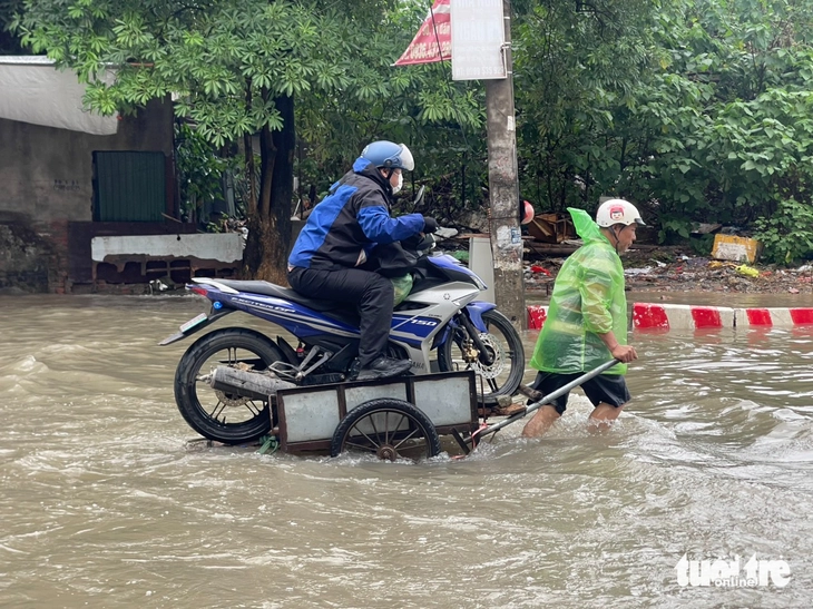 Tấp nập 'cứu' xe máy qua điểm ngập, giá... 200 nghìn cho quãng đường hơn trăm mét - Ảnh 2.