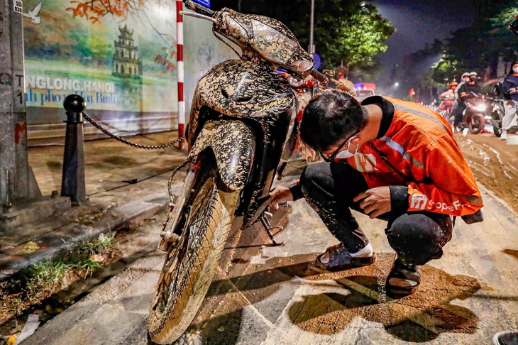 Bùn nhão tràn trên phố trung tâm Hà Nội làm nhiều người ngã dúi dụi, công an vào cuộc - Ảnh 1.