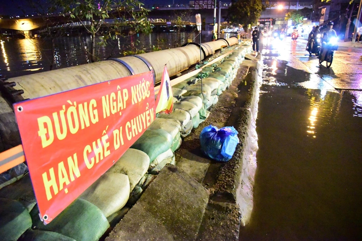 Đắp bao cát ngăn nước kênh Tẻ tràn vào đường Trần Xuân Soạn khi triều cường - Ảnh 3.