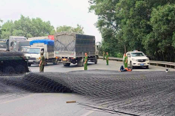 Hàng chục tấn thép từ xe container rơi xuống đường, hai người đi xe máy bị thương - Ảnh 1.