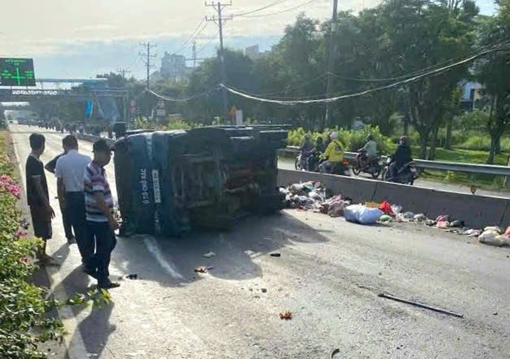 Xe tải chở rác lật ngang gần cầu vượt ngã tư Ga, quận 12, giao thông ùn ứ - Ảnh 1.