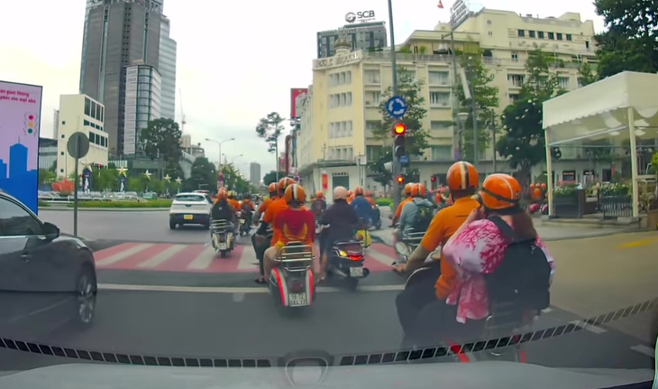 10 người mặc áo màu cam chạy Vespa vượt đèn đỏ ở trung tâm TP.HCM bị lập biên bản- Ảnh 1. Lập biên bản 10 người mặc áo cam chạy Vespa vượt đèn đỏ ở trung tâm TP.HCM - Ảnh 1.