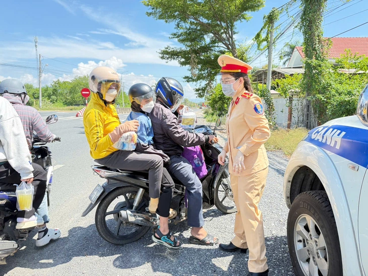 Cảnh sát giao thông phát nước suối, áo mưa miễn phí trên quốc lộ 1 cho người dân về quê nghỉ lễ - Ảnh 1. Cảnh sát giao thông phát nước, bánh, sữa cho người dân về quê nghỉ lễ - Ảnh 1.