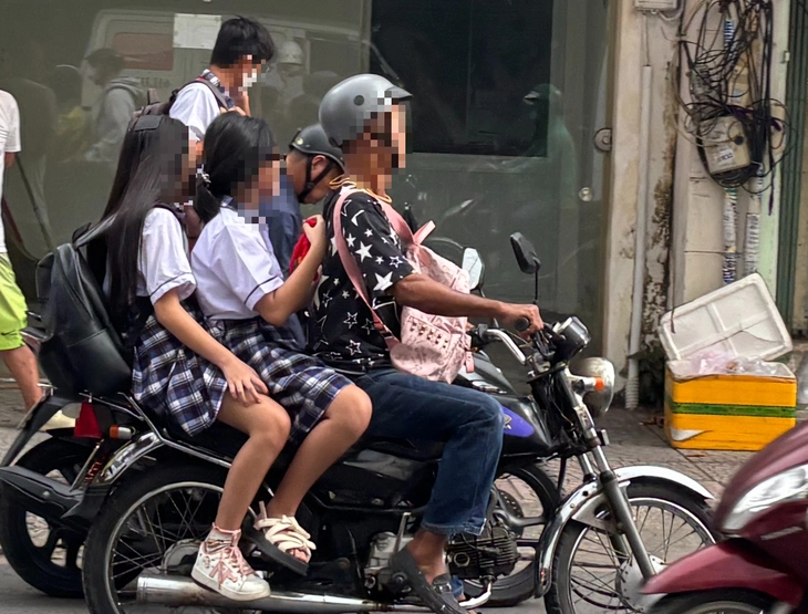 Nhiều phụ huynh 'vô tư' chở con chạy ngược chiều, leo vỉa hè, không đội mũ bảo hiểm đến trường - Ảnh 1.