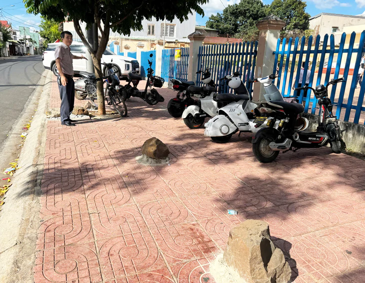 Hơn chục tảng đá được trát vữa cố định 'thù lù' trên vỉa hè trước trường - Ảnh 1.