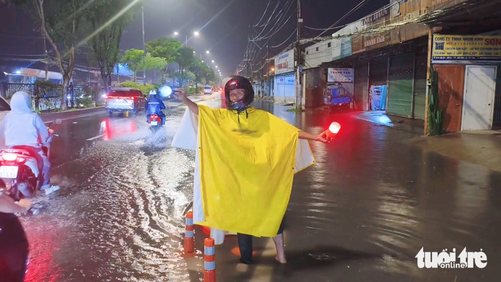Người đàn ông ở Tân An Hội bì bõm trong đêm hướng dẫn xe tránh đoạn đường ngập - Ảnh 1.