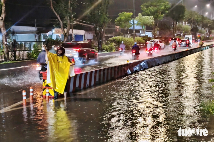 Người đàn ông ở Tân An Hội bì bõm trong đêm hướng dẫn xe tránh đoạn đường ngập - Ảnh 2.