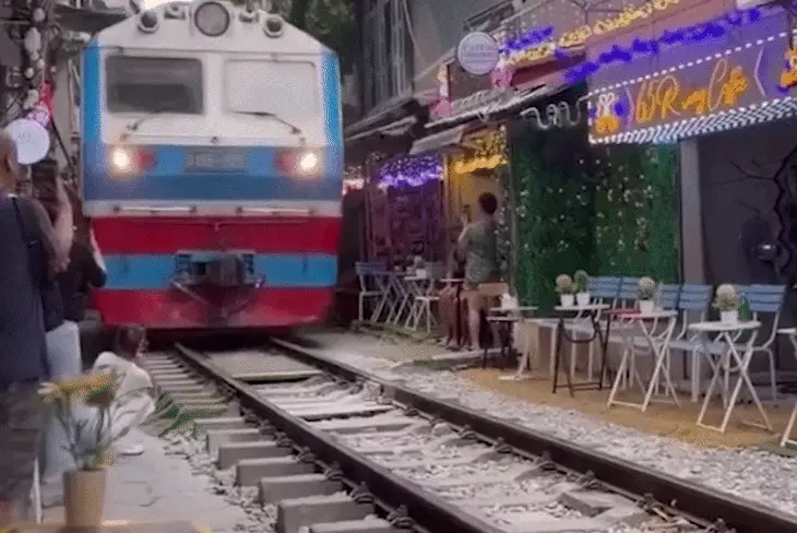 Cô gái ngồi sát đường ray, bị tàu hỏa húc văng điện thoại ở phố cà phê đường tàu - Ảnh 1.