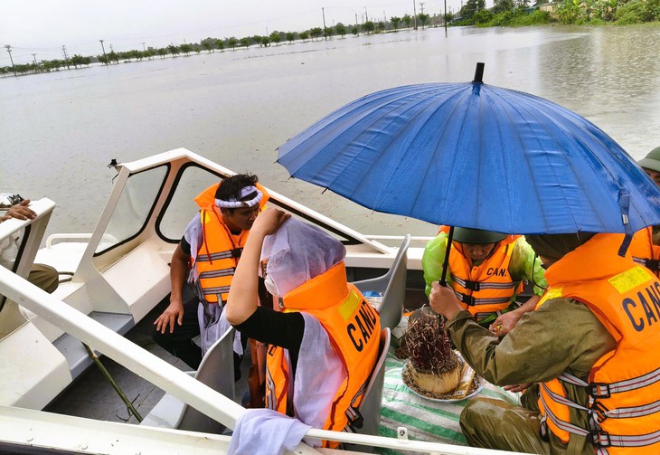 Cảnh sát dùng xuồng máy vượt nước lũ hỗ trợ đưa tro cốt về nhà tổ chức tang lễ - Ảnh 1.