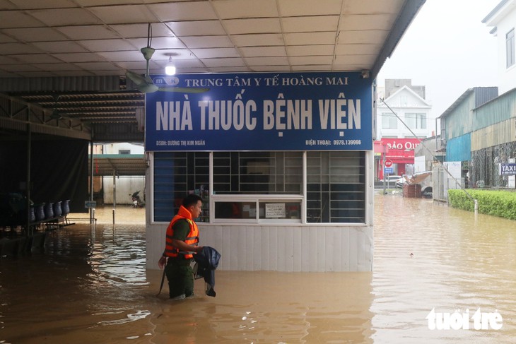 Trung tâm y tế ngập gần nửa mét, công an dùng thuyền đưa bệnh nhân ra vào - Ảnh 13.