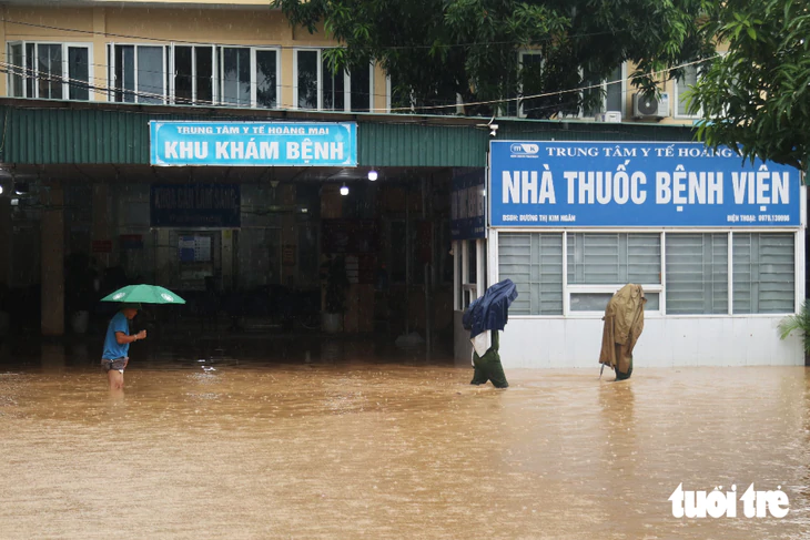 Trung tâm y tế ngập gần nửa mét, công an dùng thuyền đưa bệnh nhân ra vào - Ảnh 14.