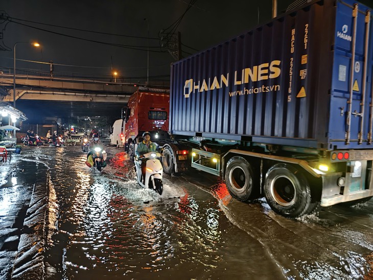 Ngã tư Nguyễn Văn Quỳ - Đào Trí ngập do triều cường, người dân dò dẫm né ổ gà, tránh xe container - Ảnh 1.