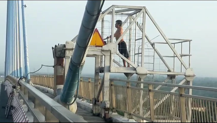 Người đàn ông leo lên lan can cầu Mỹ Thuận 1 tập thể dục, tiềm ẩn nguy hiểm - Ảnh 1.
