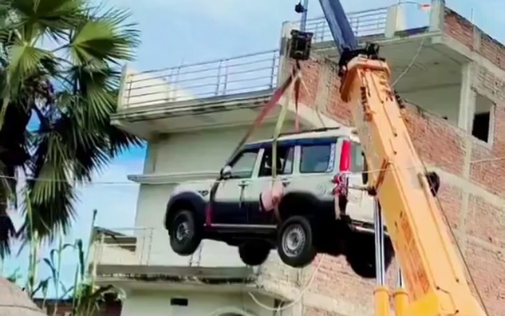 Sợ ô tô mới mua bị trộm, chủ xe thuê cần cẩu đưa thẳng lên nóc nhà - Ảnh 1.