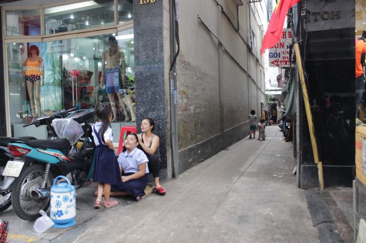 Chị Hường đang chải tóc cho con gái trước hẻm vì trong nhà quá chật và tối - Ảnh: My Lăng