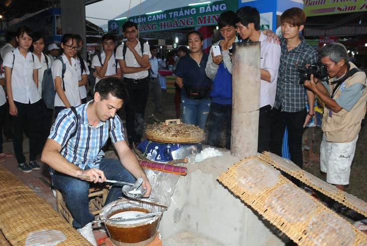 Một du khách nước ngoài học cách làm bánh tráng phơi sương tại một chương trình giới thiệu về nghề truyền thống