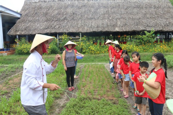 Anh Lương Việt Tấn (áo trắng) thuyết minh về công dụng các loại rau cho khách du lịch-YẾN TRINH