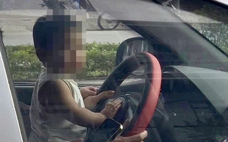 Woman summoned for letting child sit at steering wheel of moving car in Hanoi
