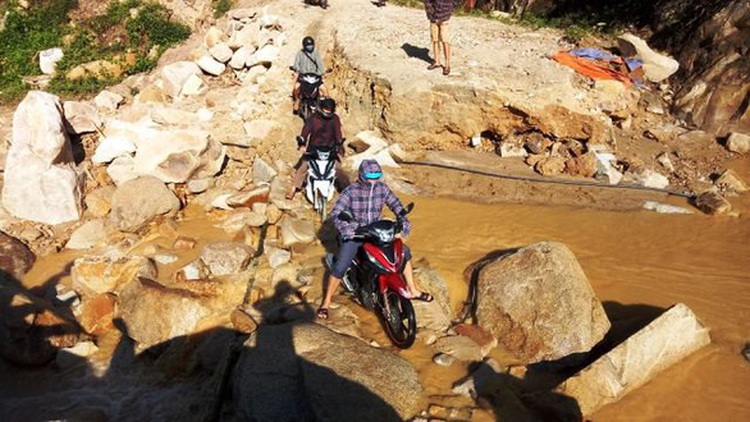Vietnam teachers carry motorbikes across muddy paths after storm cut off access to school