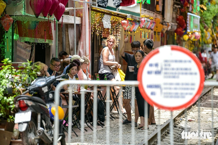 Foreign tourists persist at Hanoi trackside café street after woman purposely approaches oncoming train