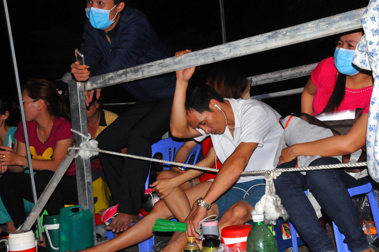 A parent rests against the metal fence for a quick nap. Photo: Tuoi Tre