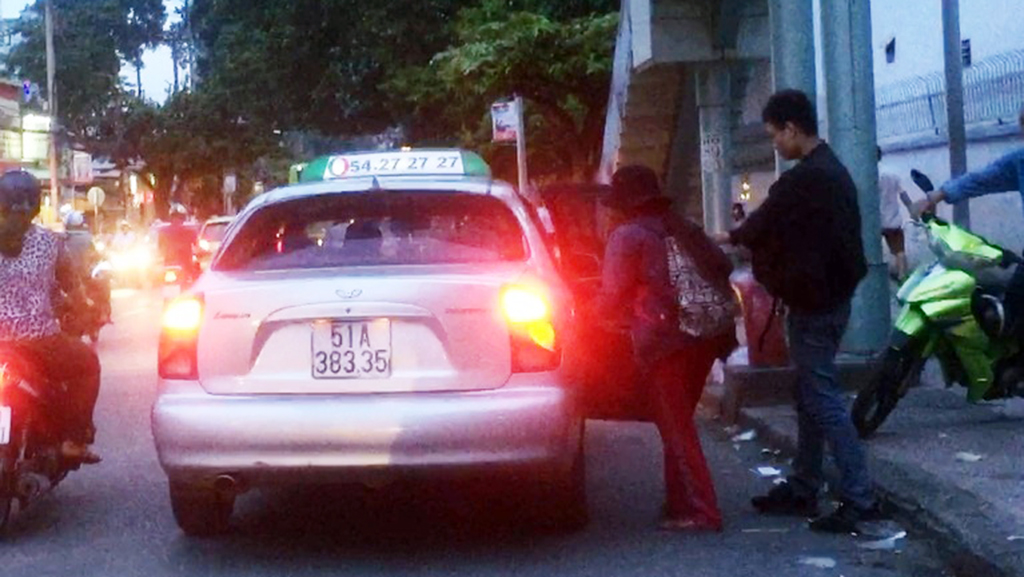 An unlicensed taxi picks up a passenger in front of the Oncology Hospital in Binh Thanh District, Ho Chi Minh City. Photo: Tuoi Tre
