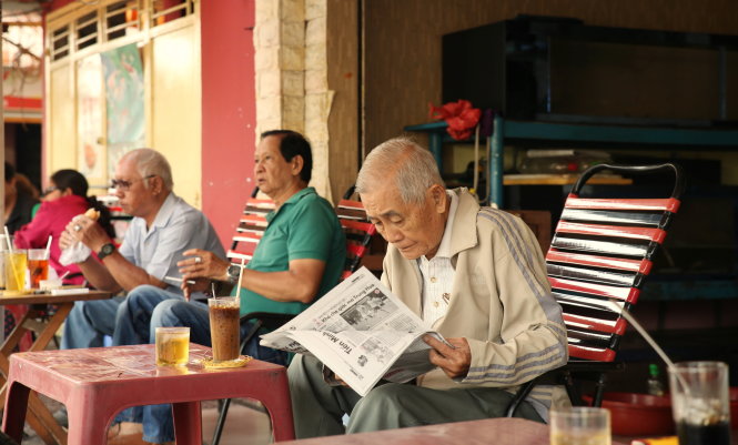 A man reads a newspaper next to a glass of ca phe sua da in Ho Chi Minh City. Photo: Tam Bui - Trung Nguyen