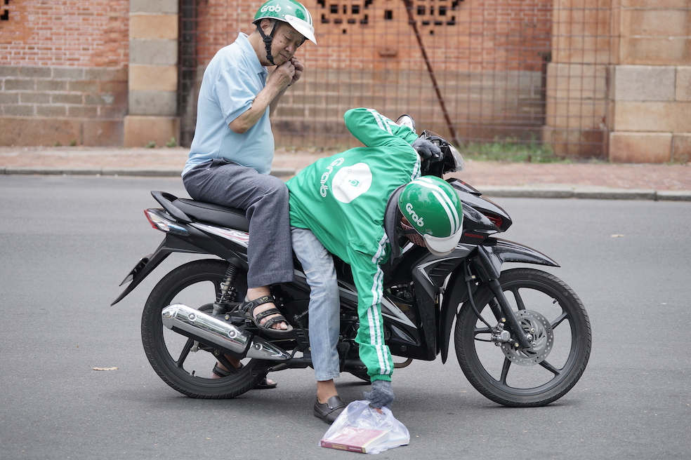 A GrabBiker is pictured picking up stuff for a passenger in District 1, Ho Chi Minh City, May 11, 2017. Photo: Tien Bui/Tuoi Tre News