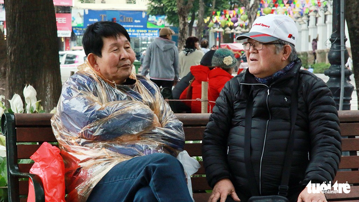 An elderly woman puts on a rain poncho.