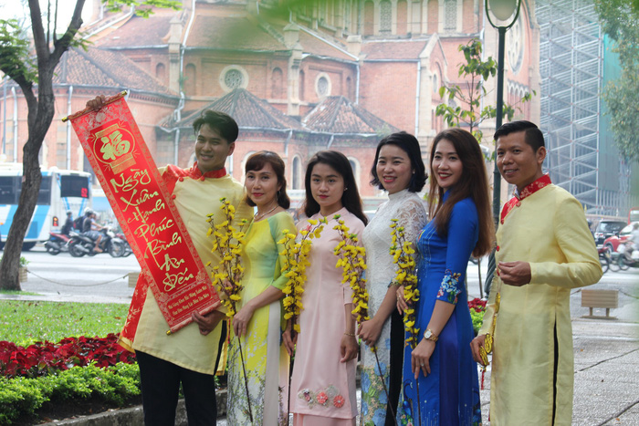 People pose for a group photo near the building with terracotta brickwork which is the Notre-Dame Cathedral Basilica of Saigon. Photo: Tuoi Tre