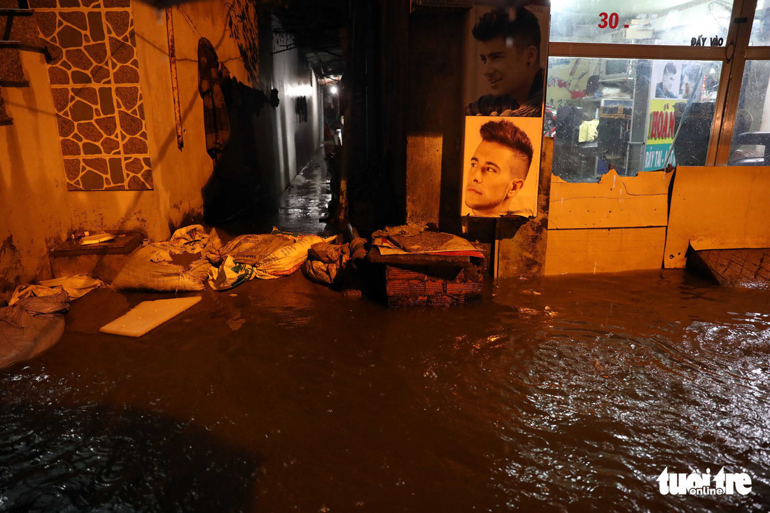 Local residents use sand bags and wooden boards to prevent floodwater from flowing into their homes.