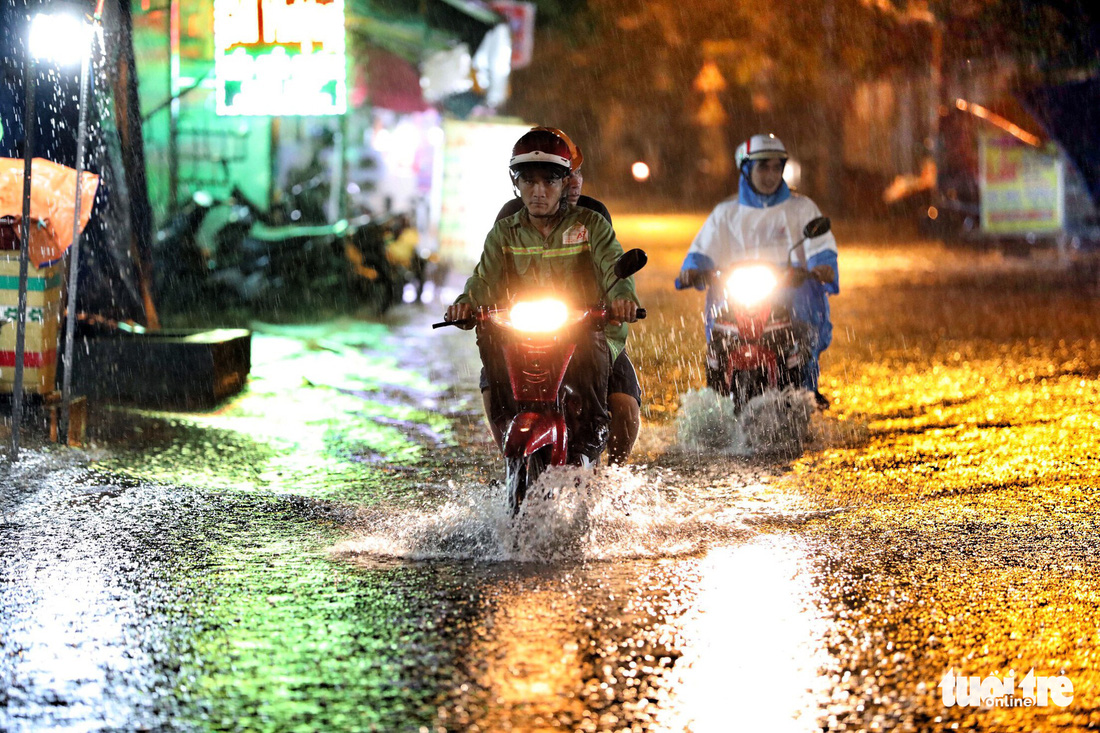 People travel along a flooded street cause by heavy downpour in Ho Chi Minh City.
