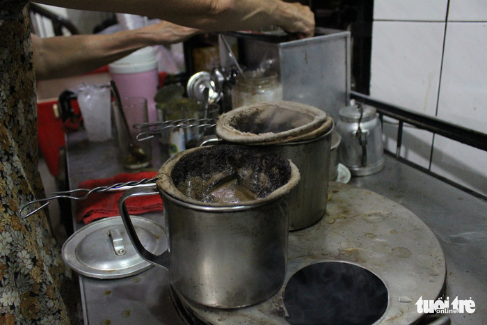 The spoon-net filter with a white cloth ballooning off a steel bubble wand is propped over an empty stainless steel jug. Photo: Tuoi Tre