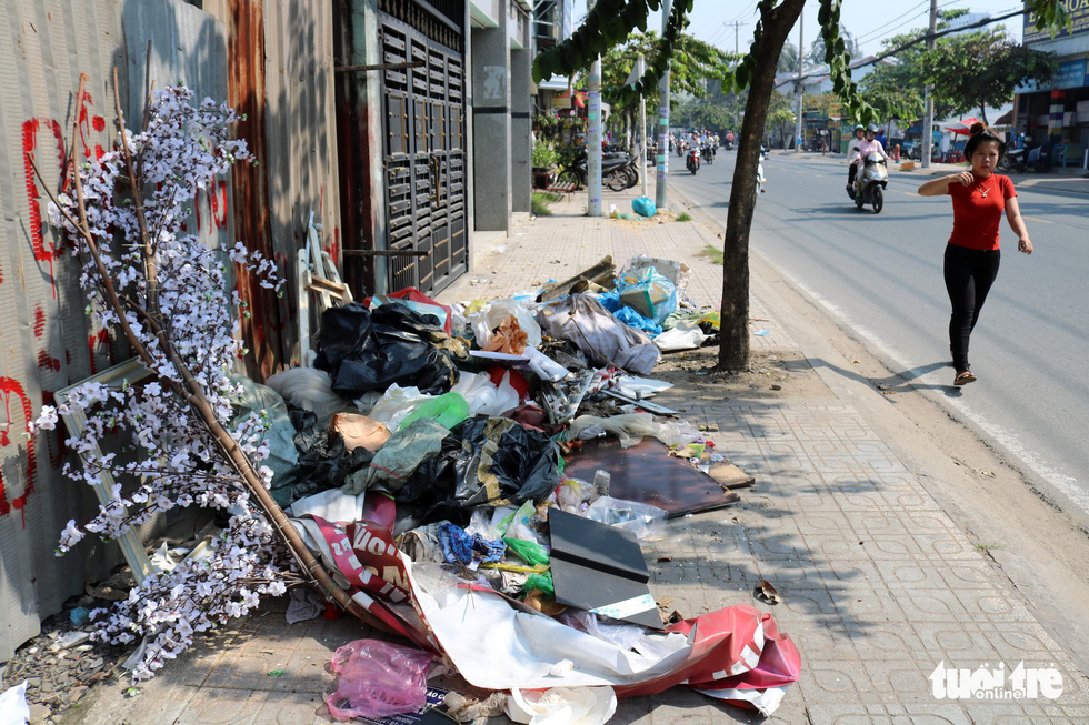 Pedestrians are unable to walk on the sidewalk as it is blocked by a malrge amount of garbage.