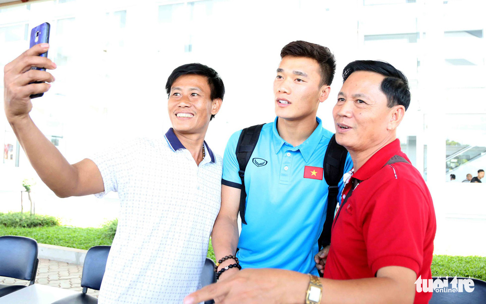 Fans take photo with Vietnamese goalkeeper Bui Tien Dung upon his team's arrival at the Wattay International Airport in Laos on November 5, 2018. Photo: Tuoi Tre