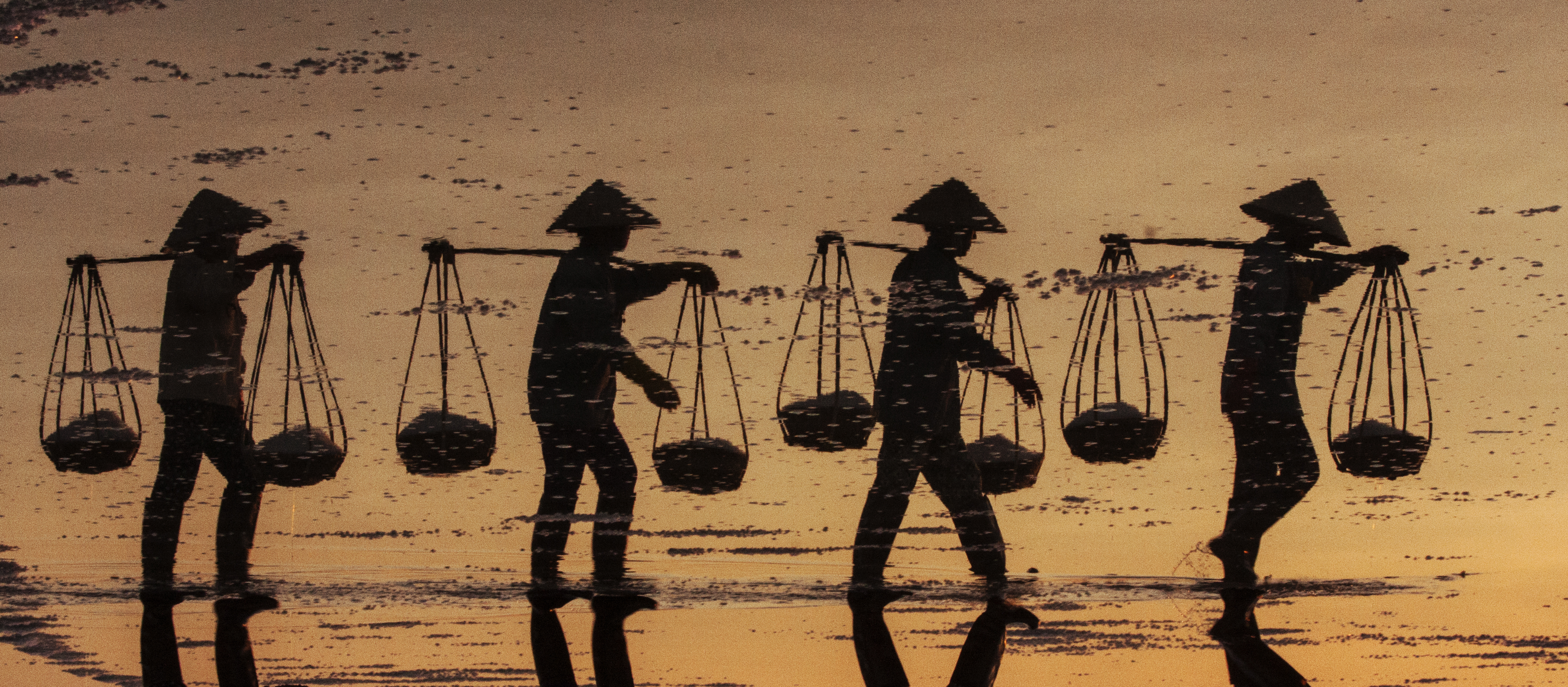 Salt workers are silhouetted against water while working in this photo Nese Ari took in Vietnam