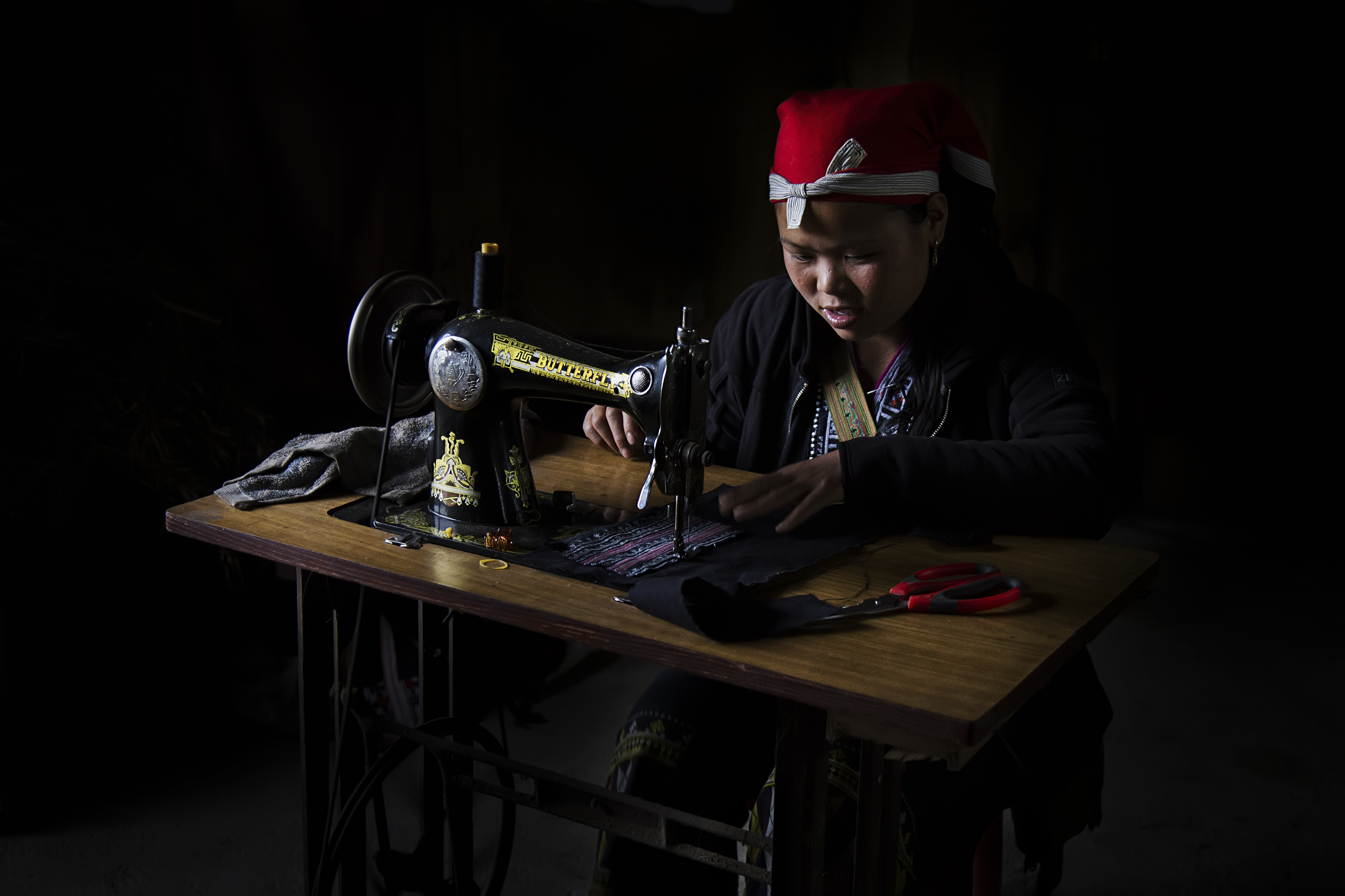 A member of an ethnic minority group in Vietnam is seen sewing clothes in this photo by Nese Ari