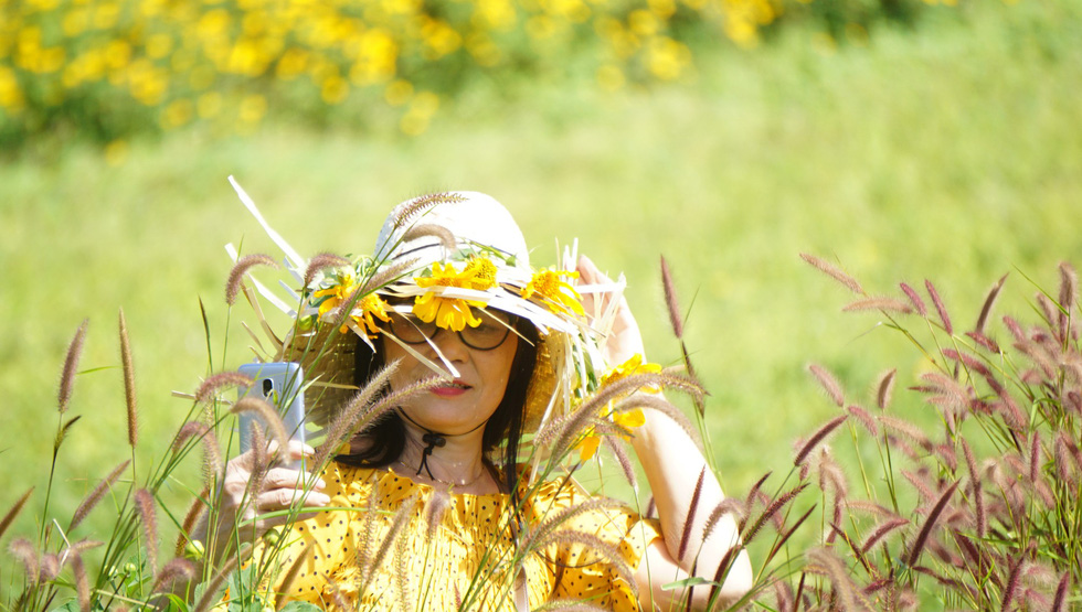 A woman takes a selfie with the flowers.