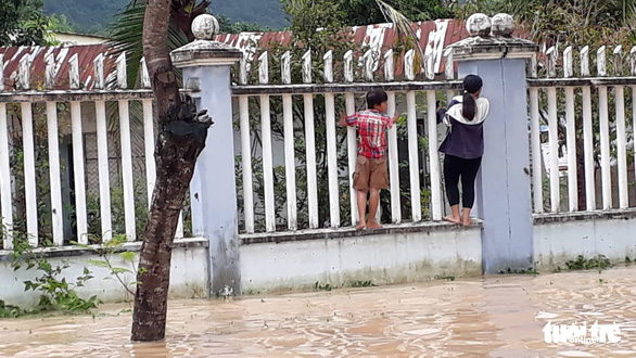 Residents climb along a fence to cross a flooded street in Nha Tranh City, Khanh Hoa Province. Photo: Tuoi Tre