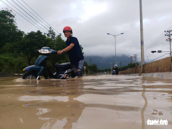 A man pushes in motorbike along inundated Nguyen Tat Thanh Street in Nha Trang. Photo: Tuoi Tre