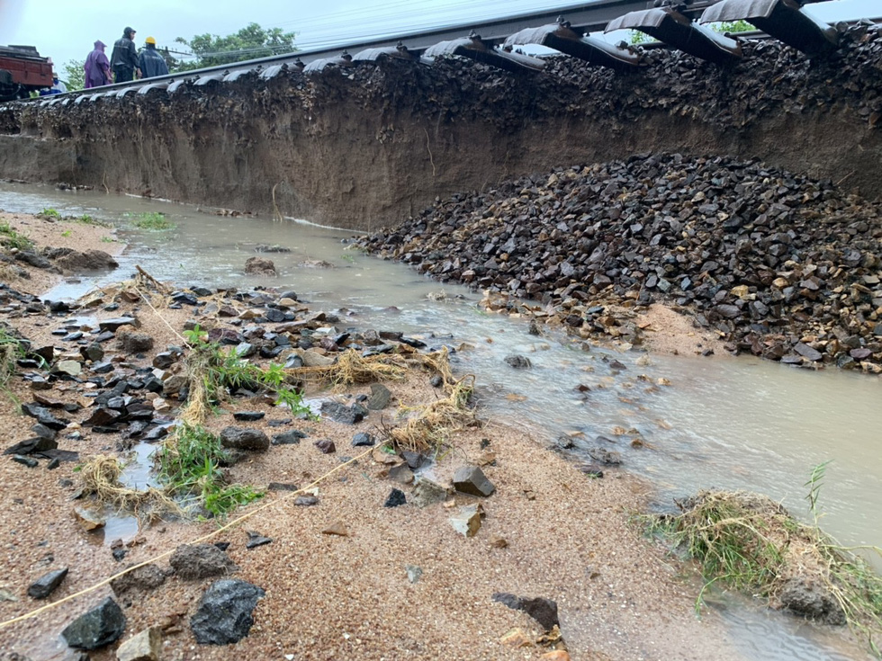 Floodwater washes away soil underneath the railway track in Ninh Thuan Province. Photo: Tuoi Tre