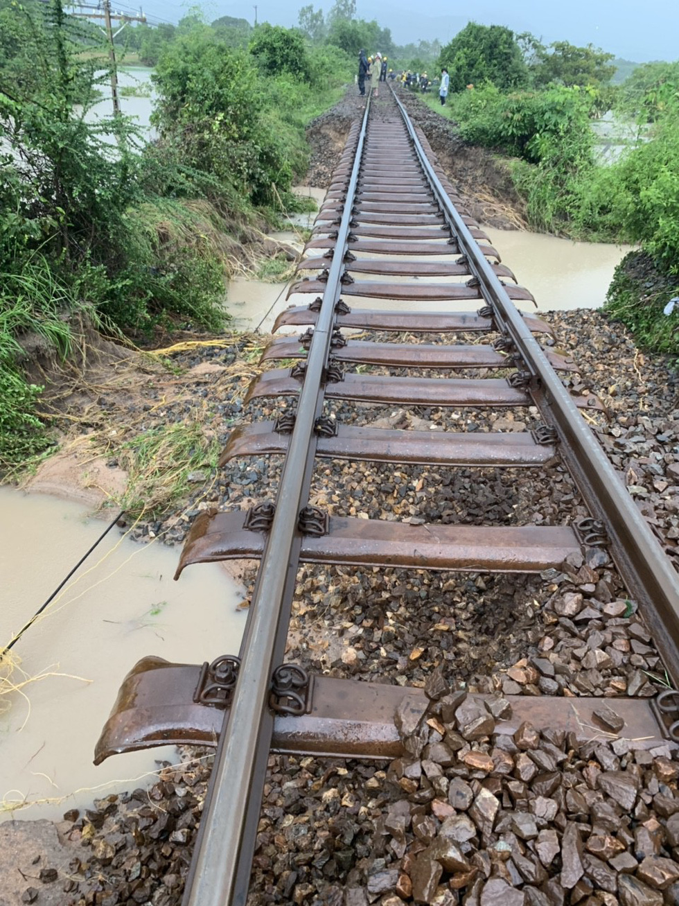 Floodwater washes away soil underneath the railway. Photo: Tuoi Tre