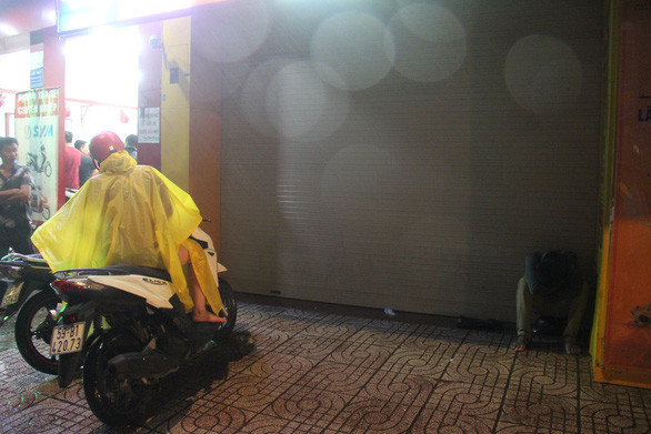 A man sleeps sitting under a porch near a motorbike repair shop in Ho Chi Minh City on November 25, 2018. Photo: Tuoi Tre