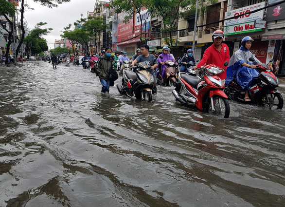 Commuters push their scooters through the floodwater in Ho Chi Minh City on November 26, 2018. Photo: Tuoi Tre