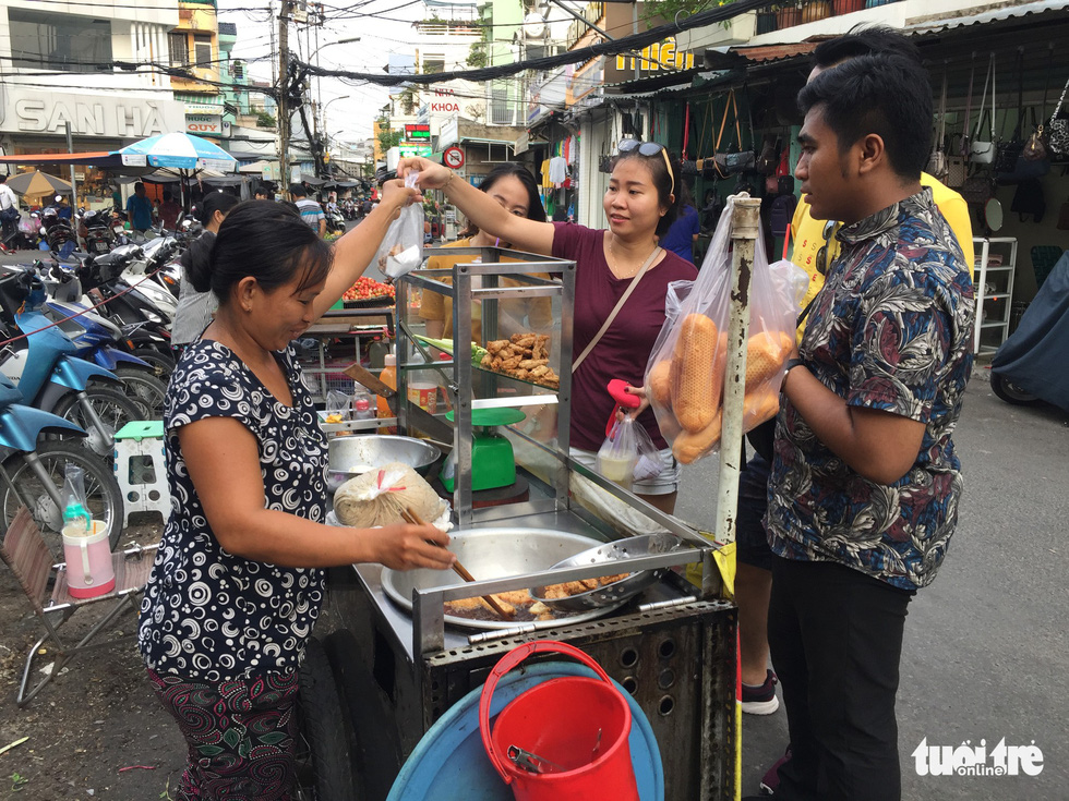 Danny Ramadhan (right) watches as his host family haggles for cooking ingredients at a market. Photo: Tuoi Tre