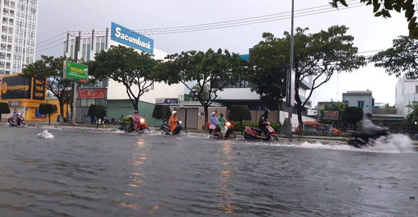Vehicles travel along inundated Nguyen Huu Tho Street. Photo: Tuoi Tre