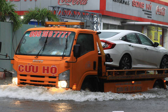 A rescue truck carries a car that breaks down due to rainwater. Photo: Tuoi Tre