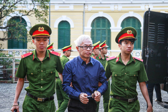 Tran Phuong Binh, former chief executive officer of DongA Bank is escorted by policemen during his trial in Ho Chi Minh City on December 10, 2018. Photo: Tuoi Tre